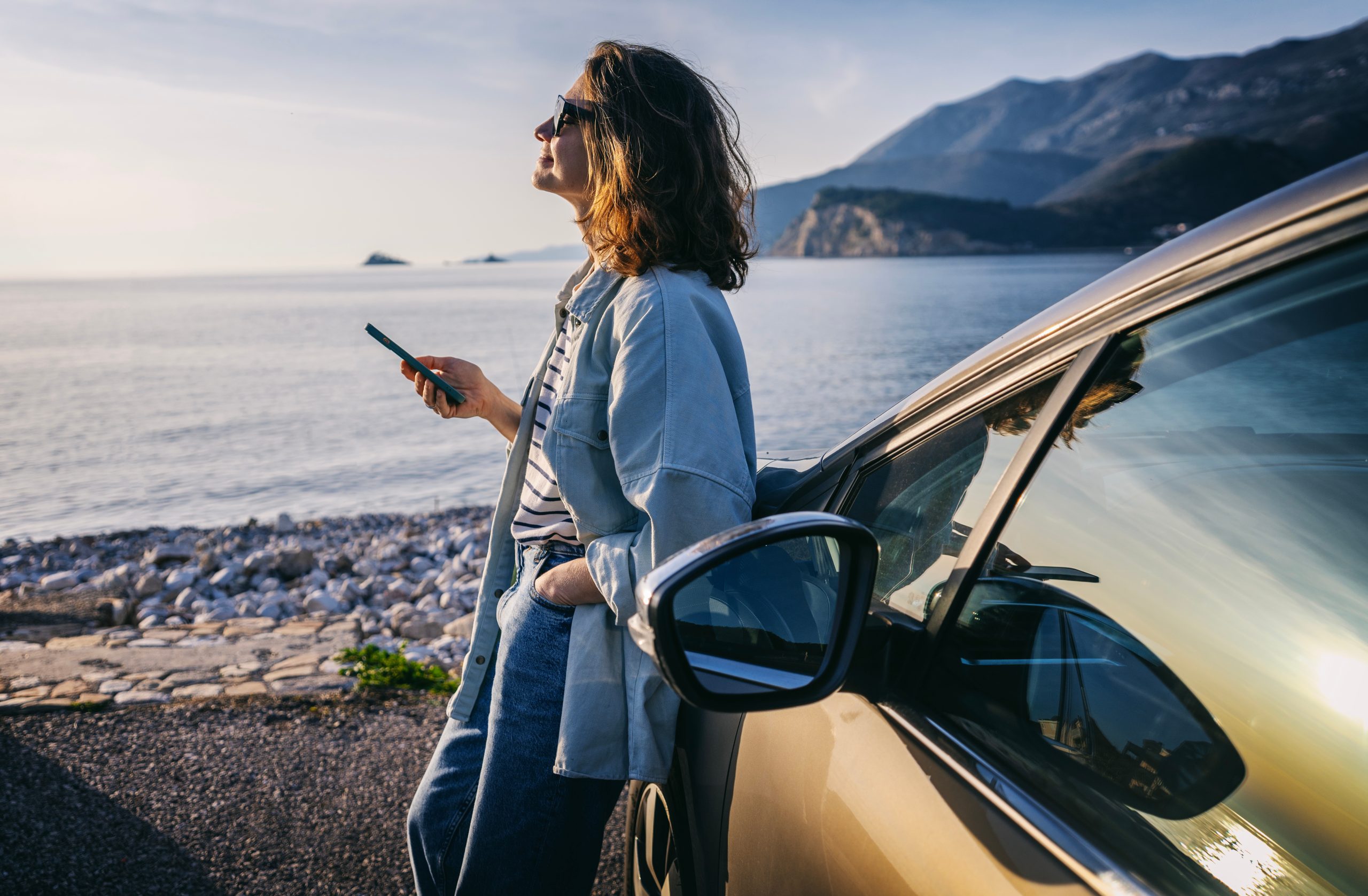 oung woman traveler in a hat standing by her car during summer sea holiday